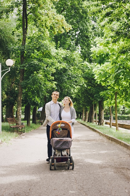 장바구니에 그녀의 아기를 산책하는 아버지와 젊은 어머니