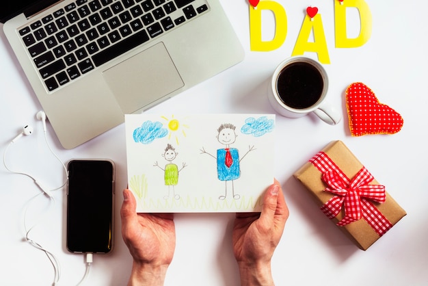 Fathers day composition with laptop and hands holding drawing