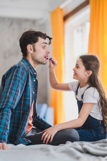 Free photo fathers day concept with daughter painting fathers lips