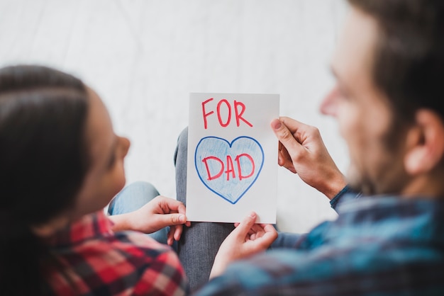 Fathers day concept with father and daughter looking at hand drawn card