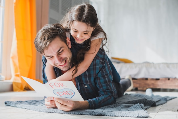 Concetto di giorno di padri con il padre che legge la carta disegnata a disposizione