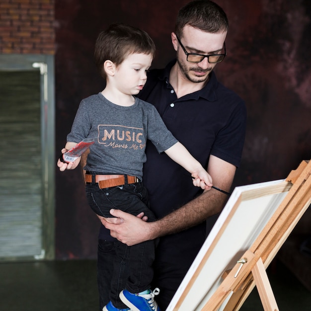 Free photo fathers day concept with father and son in front of canvas