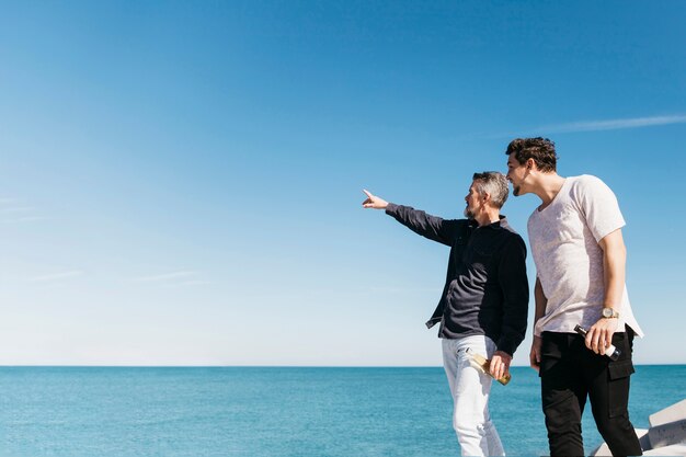 Fathers day concept with father and son pointing towards sea