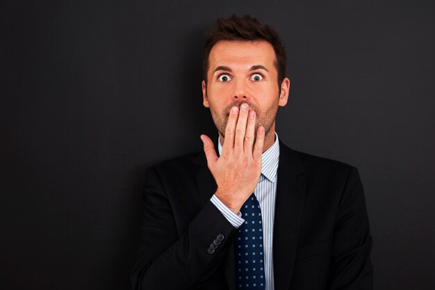 Fearful businessman covering his mouth