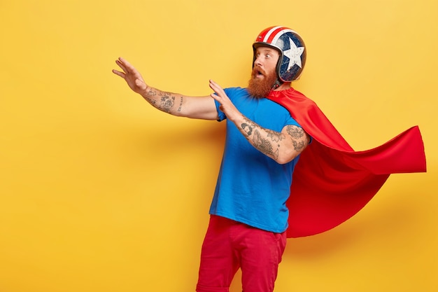 Fearful man wears red cape and helmet