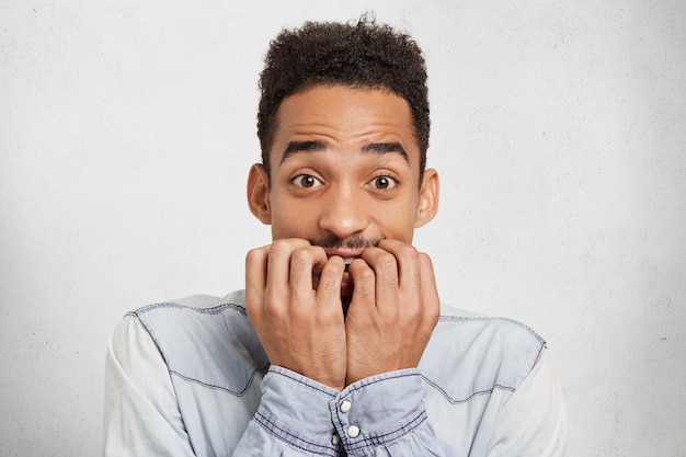 Fearful worried man bites nails in anxiety, feels nervous