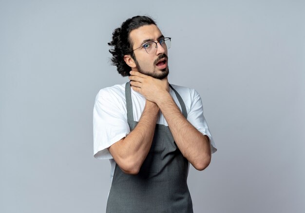 Fed up young caucasian male barber wearing glasses and wavy hair band in uniform choking himself isolated on white background with copy space