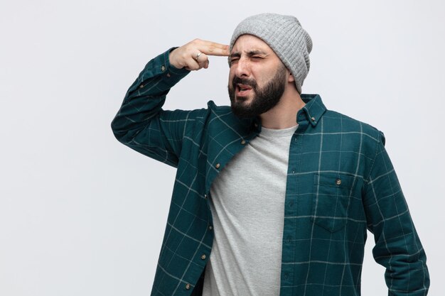 Fedup young man wearing winter hat showing suicide gesture isolated on white background