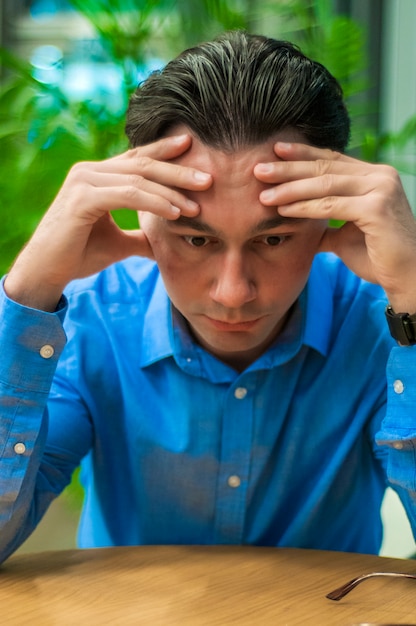 Free photo feeling exhausted. frustrated young man keeping eyes closed while sitting at his working place in office