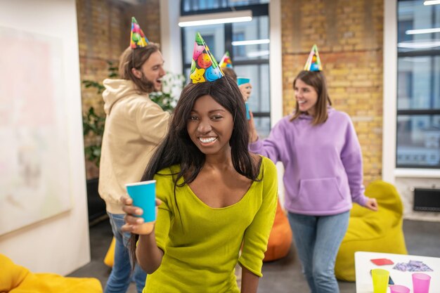 Feeling festive. Young people celebrating in the office and looking happy and enjoyed