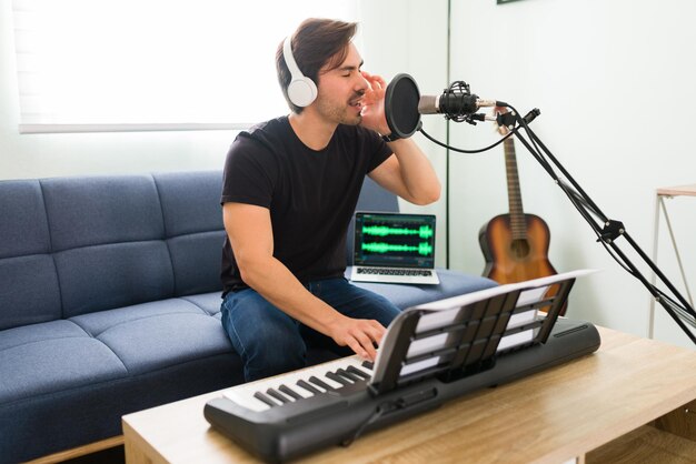 Feeling inspired by my favorite song. Young man and musician singing his new composition on a microphone while playing the piano at home