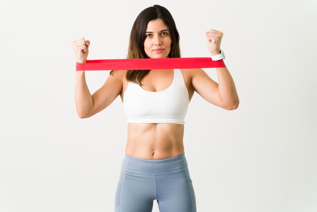 Feeling motivated during a workout. Athletic young woman holding a red resistance rubber band on her arms and making eye contact