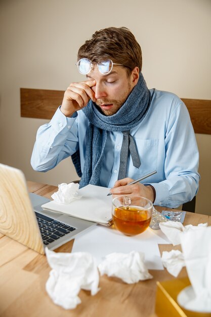 気分が悪くて疲れている。彼の目をマッサージする欲求不満の悲しい不幸な病気の若い男