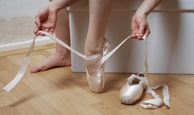 Feet of ballerina putting on ballet or pointe shoes