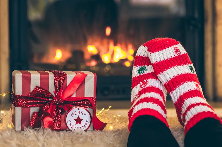 Free Photo feet in christmas socks and gift box in front of the fireplace closeup