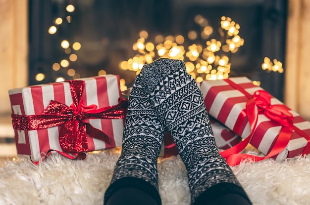 Free photo feet in christmas socks and gift boxes in front of the fireplace close up