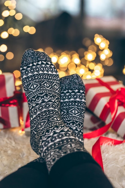 Free photo feet in christmas socks and gift boxes in front of the fireplace close up