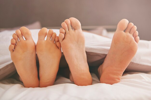 Feet of couple in comfortable bed
