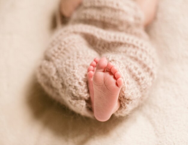 Feet of dreamy child enveloped in woolen scarf