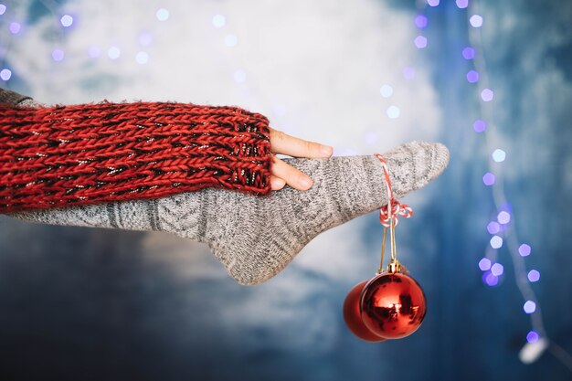 Feet holding red christmas ball