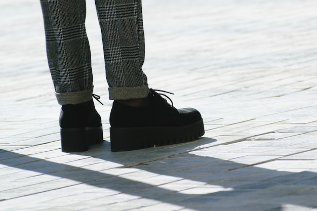 Free photo feet of a woman with black high platform shoes and grey pants in the street