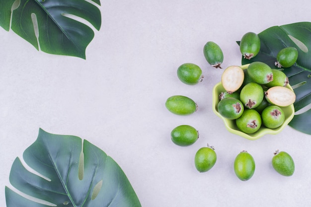 Feijoas in a green cup on grey surface