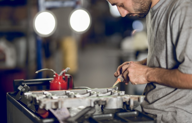 A fellow benchman adding oil to the engine of a car