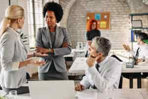 Free photo female african american entrepreneur and her colleagues communicating on a business meeting in modern office there are people in the background