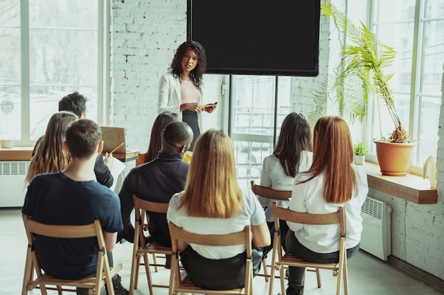 Female african-american speaker giving presentation in hall at university workshop