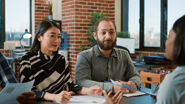 Female applicant attending job interview appointment, giving cv files to group of businesspeople at employment meeting. Team of employees analyzing resume of candidate for company recruitment.