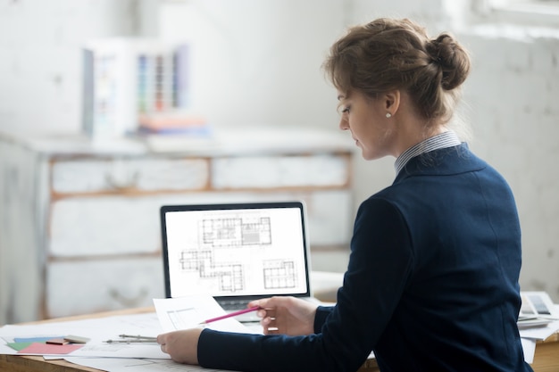 Free photo female architect reading blueprints