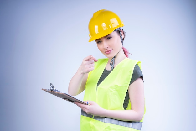 Female architect woman in a yellow helmet looks and points at front