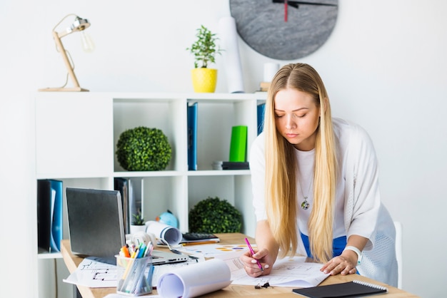 Female architect working on blueprint in office