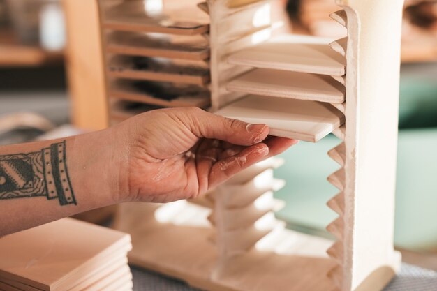 Female artisan arranging the painted white ceramic tiles in the small rack