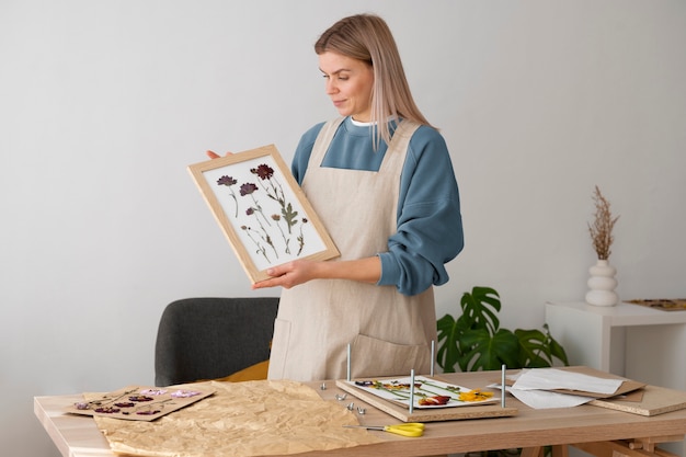 Free photo female artisan with frame made of pressed flowers