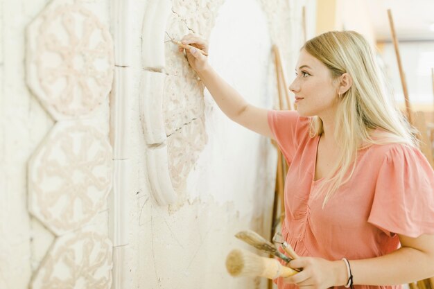 An female artist carving on wall with tool