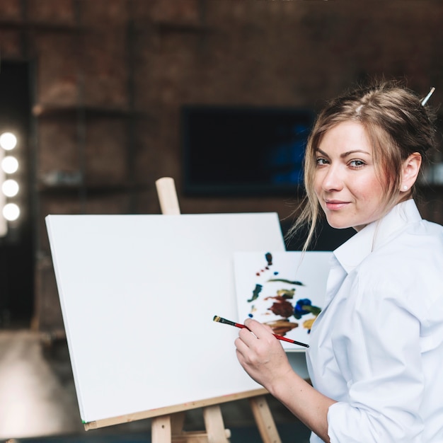 Free photo female artist in front of blank canvas