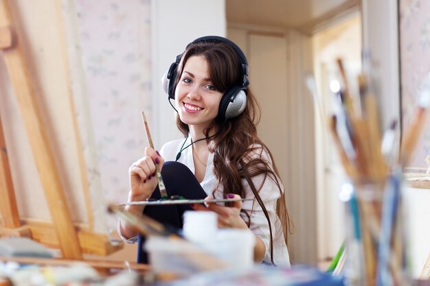 Female artist in headphones paints picture