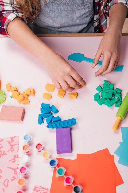 female artist holding colorful clay piece over desk