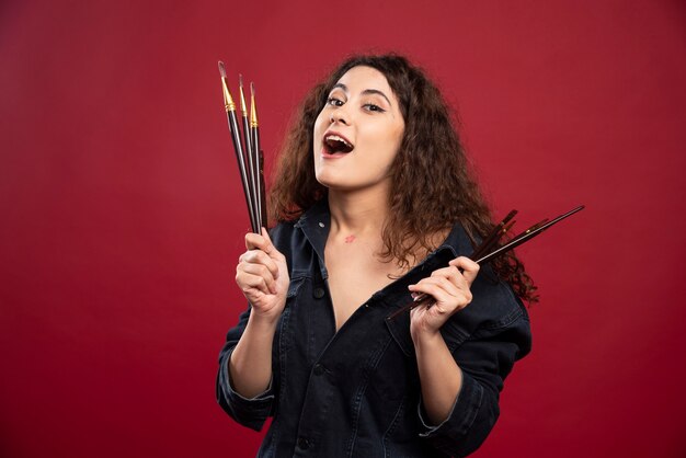 Female artist holding paintbrushes.