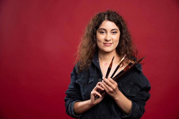 Female artist holding paintbrushes.