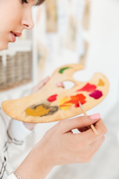 Female artist holding palette and mixing paint colors