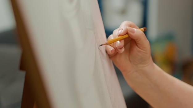 Female artist holding pencil to draw vase outline sketch on canvas, drawing professional artwork masterpiece creation. Using artistic tools and equipment for hobby. Handheld shot. Close up.