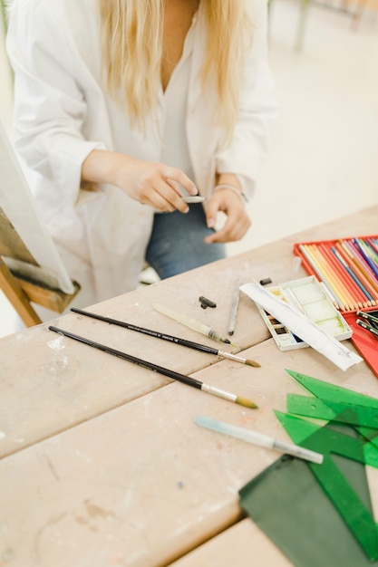 Female artist holding pencil in hand near the workbench