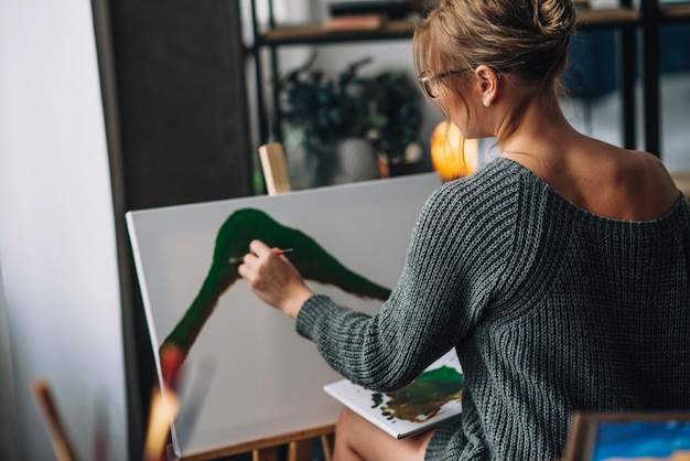Free photo female artist painting on canvas