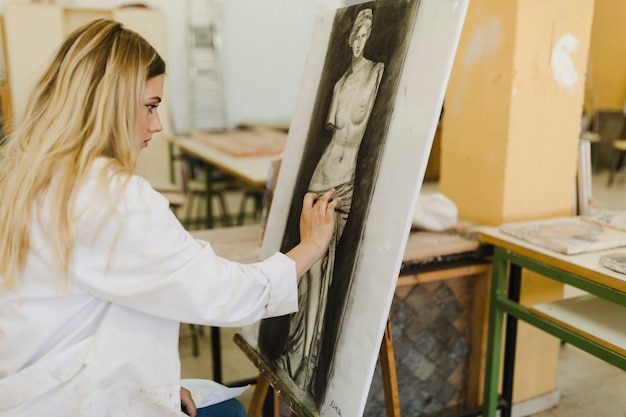 Pittura dell'artista femminile sul cavalletto nell'officina