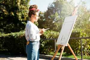 Free photo female artist painting outdoors