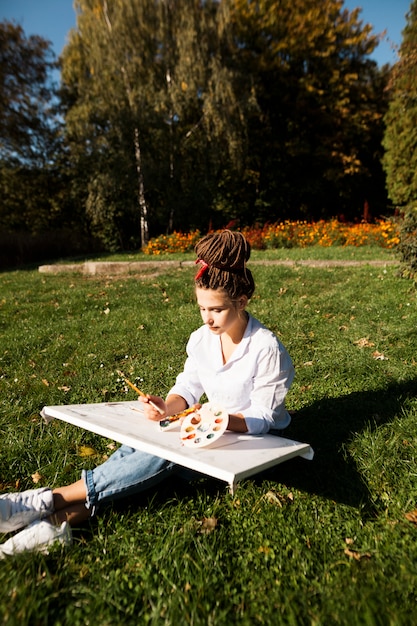 Free photo female artist painting outdoors