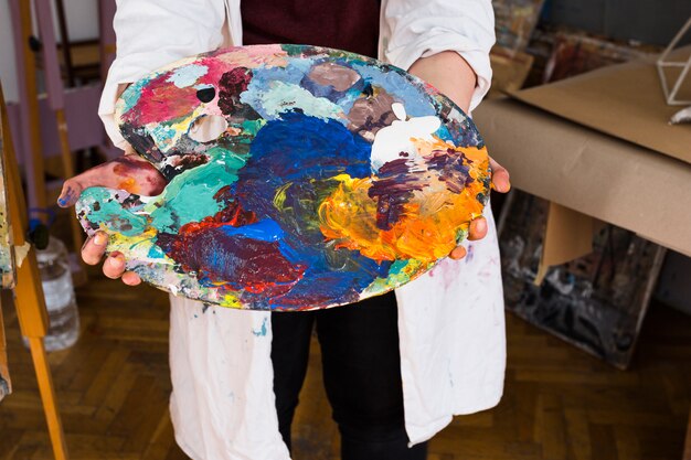 Female artist's hand showing messy color palette
