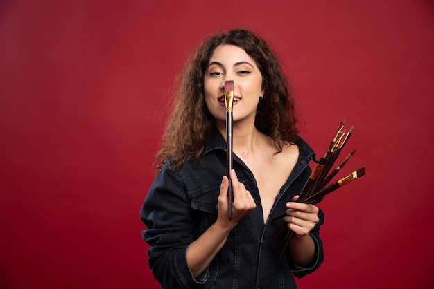 Free photo female artist touching her nose with brush.